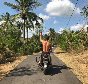 Rory riding a scooter down a tropical road